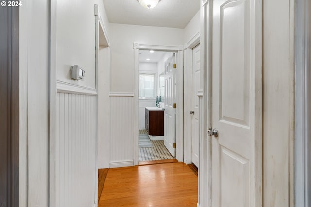 corridor featuring a textured ceiling and light hardwood / wood-style flooring