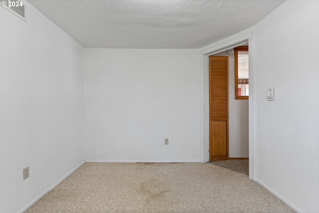 unfurnished room with a textured ceiling and carpet flooring