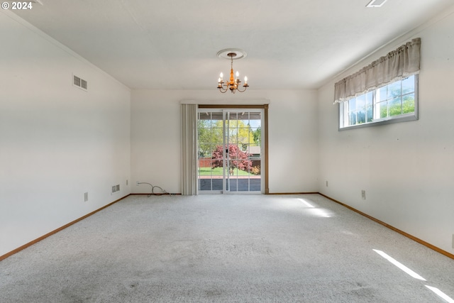 carpeted empty room featuring a notable chandelier