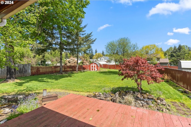 wooden terrace featuring a lawn and a storage unit