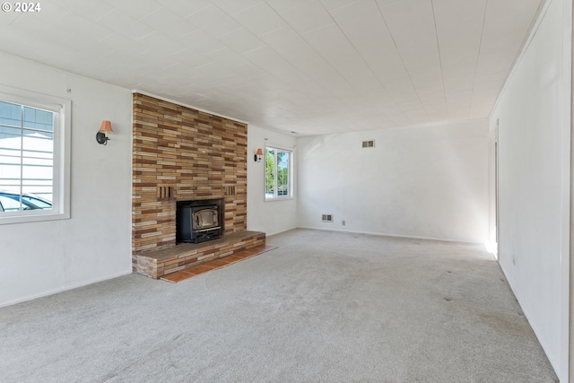 unfurnished living room with a large fireplace, a wood stove, and carpet floors