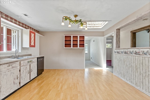 kitchen featuring a skylight, sink, light hardwood / wood-style floors, and dishwasher