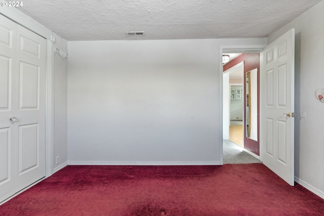 carpeted empty room featuring a textured ceiling