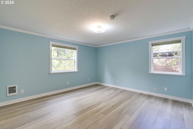 empty room with a textured ceiling, light hardwood / wood-style flooring, and a wealth of natural light