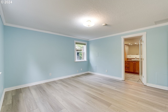 empty room with sink, light hardwood / wood-style floors, crown molding, and a textured ceiling