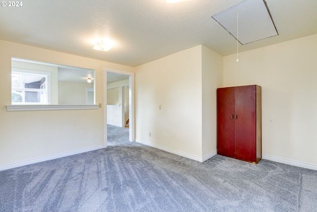 carpeted empty room featuring a textured ceiling