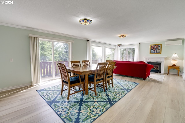 dining area featuring ornamental molding, light wood-type flooring, a textured ceiling, and a wall mounted air conditioner