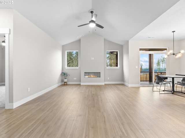 unfurnished living room with ceiling fan with notable chandelier, a healthy amount of sunlight, and light hardwood / wood-style flooring