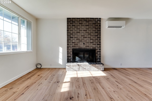 unfurnished living room with a fireplace, light wood-type flooring, and a wall mounted air conditioner