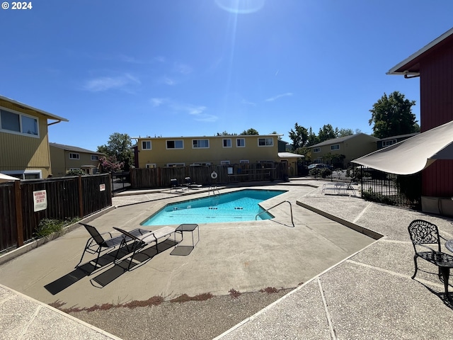 community pool with a patio and fence