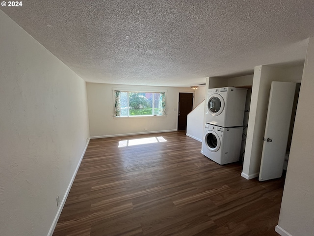 laundry room featuring stacked washing maching and dryer, dark hardwood / wood-style floors, and a textured ceiling