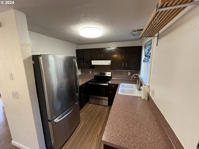 kitchen with a textured ceiling, light hardwood / wood-style flooring, sink, and appliances with stainless steel finishes