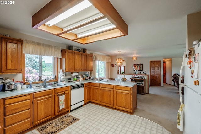 kitchen with kitchen peninsula, sink, a healthy amount of sunlight, and white appliances