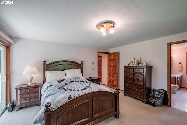 carpeted bedroom with a textured ceiling and ensuite bath