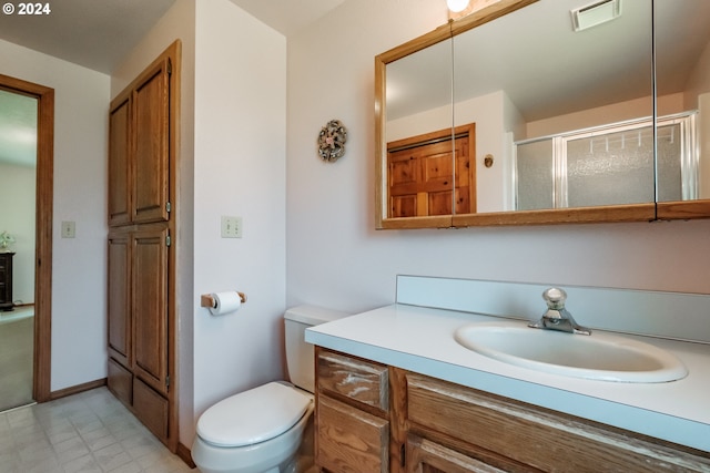 bathroom with vanity, toilet, and a shower with door