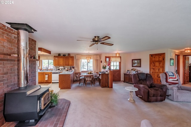 carpeted living room featuring ceiling fan and a wood stove