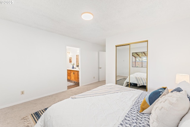 carpeted bedroom featuring ensuite bathroom, a textured ceiling, and a closet