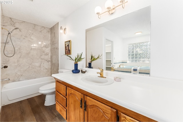 full bathroom with toilet, wood-type flooring, a textured ceiling, vanity, and tiled shower / bath combo