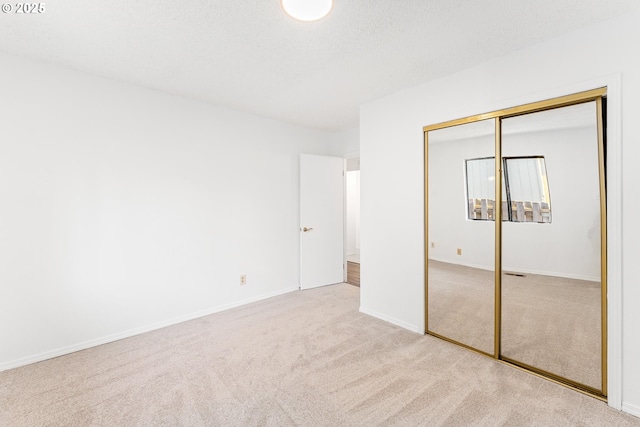 unfurnished bedroom with light colored carpet, a textured ceiling, and a closet