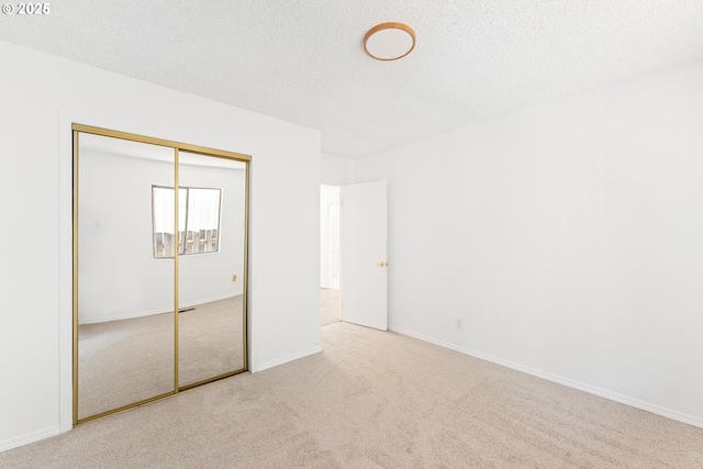 unfurnished bedroom featuring a closet, light carpet, and a textured ceiling