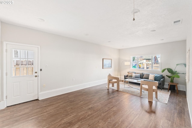 living room with a textured ceiling and dark hardwood / wood-style flooring