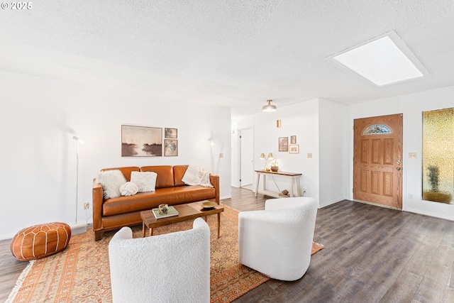 living room with hardwood / wood-style flooring, a skylight, and a textured ceiling