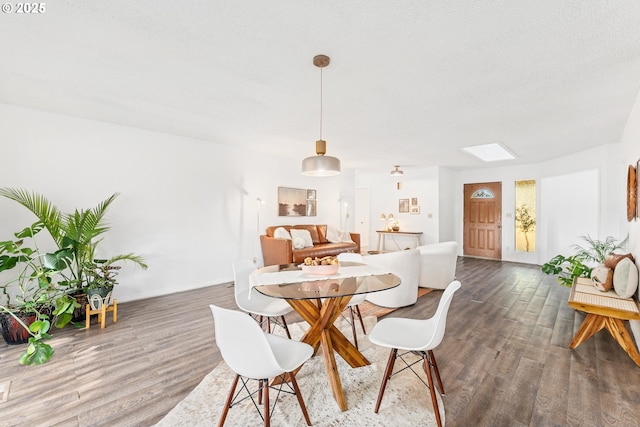 dining area with dark hardwood / wood-style floors, a skylight, and a textured ceiling