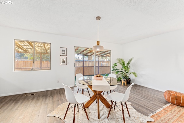 dining area with hardwood / wood-style floors and a textured ceiling