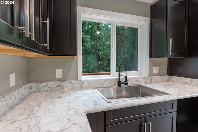 kitchen with black dishwasher, sink, light stone counters, and a wealth of natural light