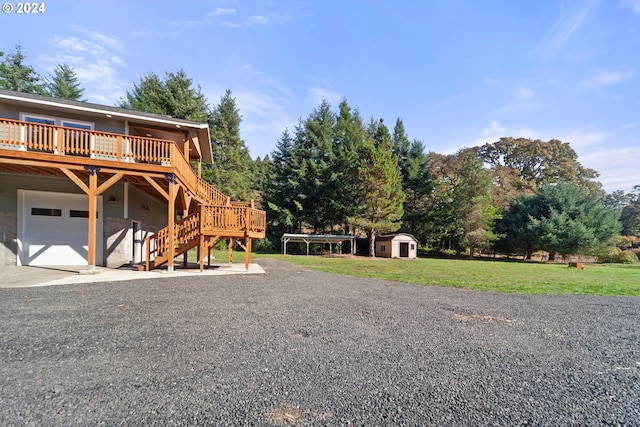 view of yard with a wooden deck, a storage shed, and a garage