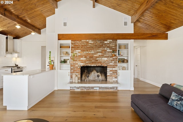 unfurnished living room featuring a brick fireplace, built in shelves, high vaulted ceiling, light hardwood / wood-style floors, and beamed ceiling