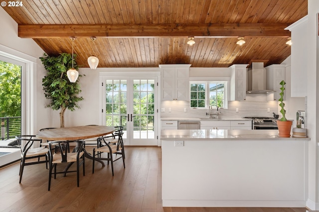 kitchen featuring wall chimney range hood, white cabinetry, wood ceiling, and pendant lighting