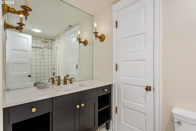 bathroom featuring tiled shower, vanity, and toilet