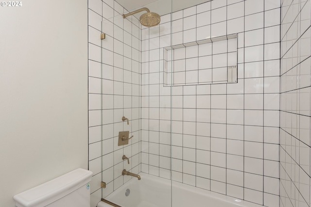 bathroom featuring tiled shower / bath combo and toilet