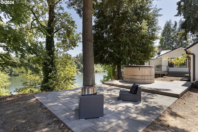 view of patio / terrace featuring a deck with water view and a hot tub