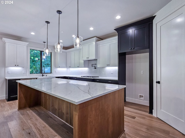 kitchen with a kitchen island, light hardwood / wood-style flooring, pendant lighting, and white cabinetry