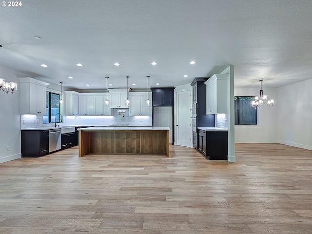 kitchen with light hardwood / wood-style floors, stainless steel dishwasher, a kitchen island, and pendant lighting