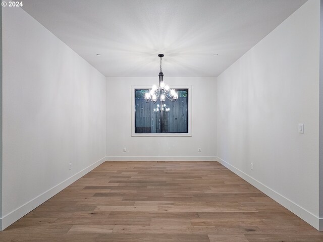 empty room featuring light hardwood / wood-style flooring and a notable chandelier