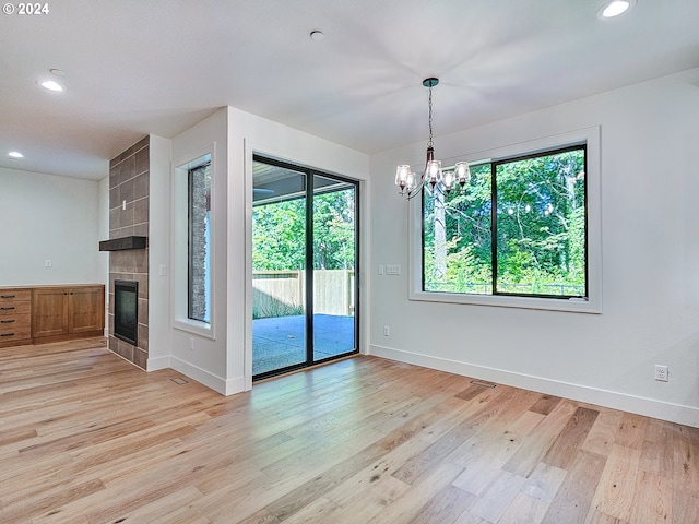 empty room featuring a notable chandelier, light hardwood / wood-style floors, and a fireplace