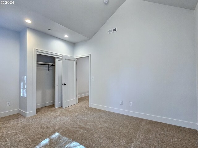 unfurnished bedroom with lofted ceiling, carpet, and a closet