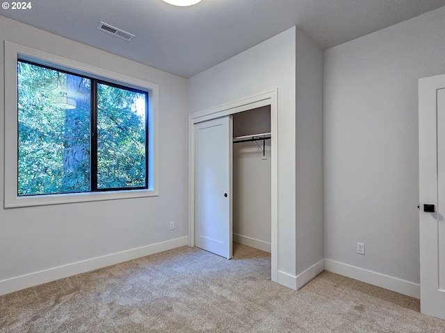 unfurnished bedroom featuring light colored carpet and a closet