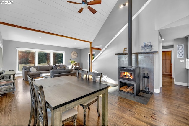 dining area with wooden ceiling, high vaulted ceiling, a wood stove, and hardwood / wood-style flooring