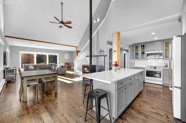 kitchen with white appliances, a wood stove, a center island, and gray cabinets