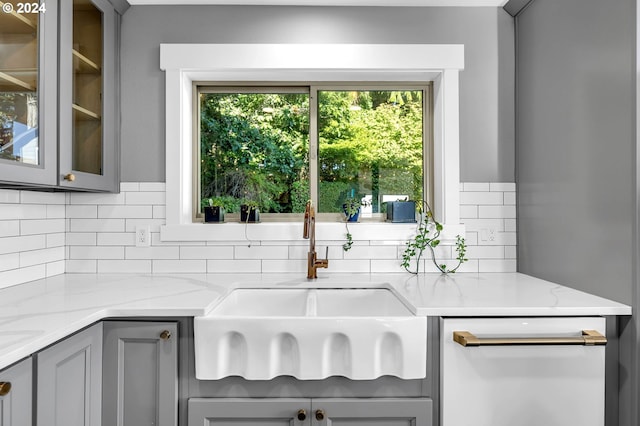 kitchen featuring tasteful backsplash, sink, gray cabinets, and light stone counters