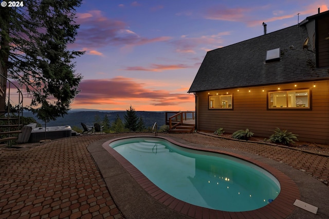 pool at dusk with a mountain view and a patio area