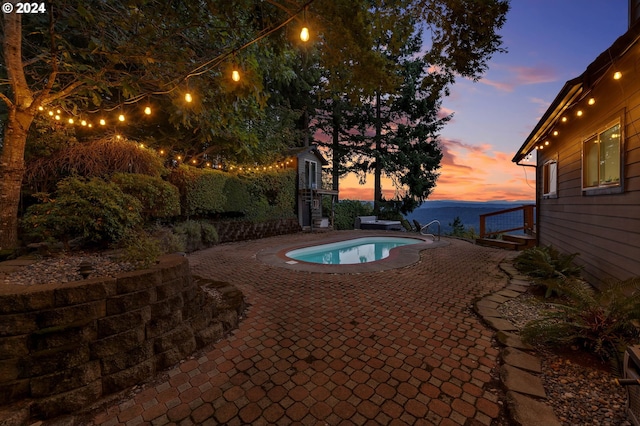 pool at dusk with a patio and a jacuzzi