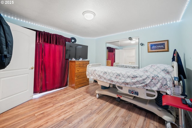 bedroom featuring a closet, light hardwood / wood-style floors, and a textured ceiling