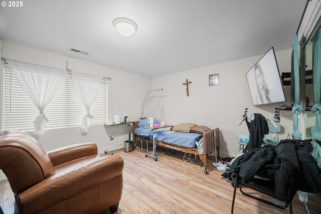 bedroom with light hardwood / wood-style floors and a textured ceiling