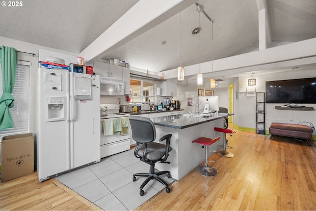 kitchen featuring a breakfast bar, a textured ceiling, white appliances, decorative light fixtures, and white cabinetry