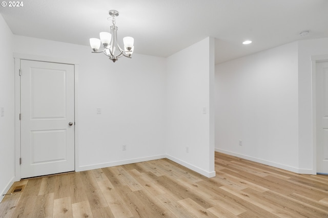 empty room with an inviting chandelier and light hardwood / wood-style floors